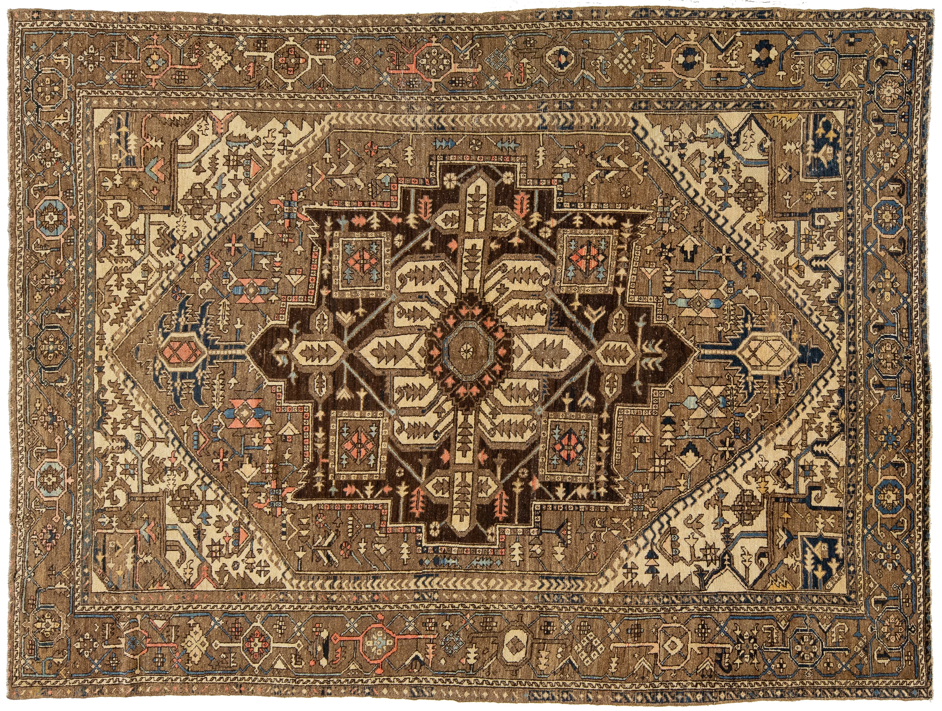 An antique Persian-style wool rug with a central medallion, featuring a warm brown, beige, and navy blue color palette with intricate geometric and floral patterns.