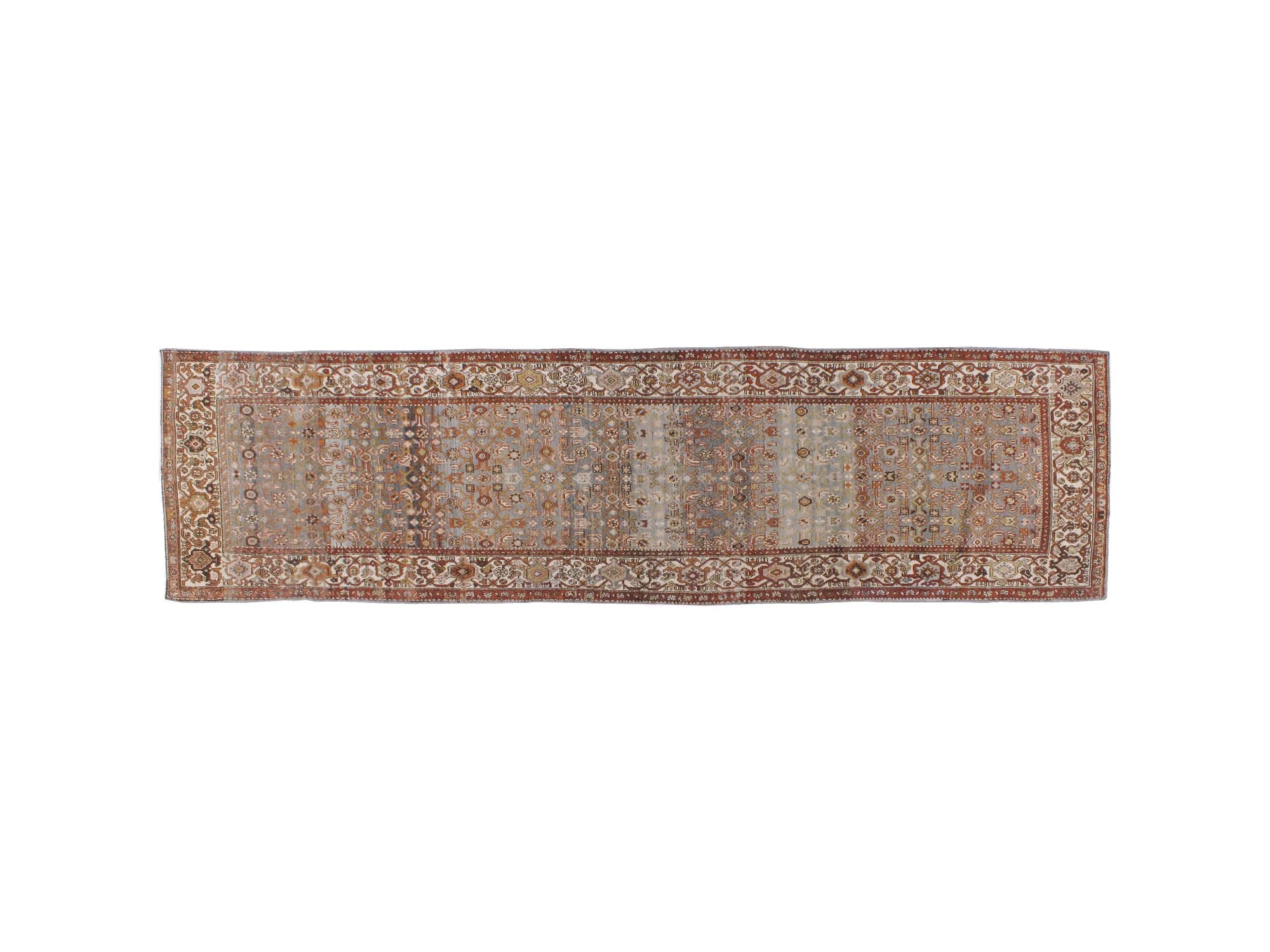 A runner rug with an intricate traditional pattern in muted tones of rust red, beige, gray, and blue, featuring a wide decorative border.