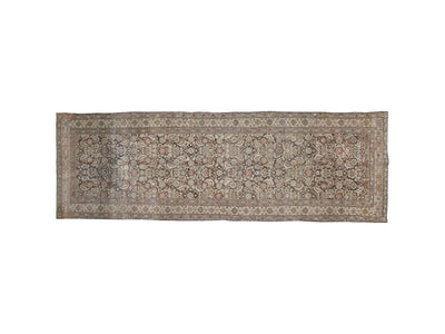 A runner oriental rug with an intricate floral and geometric pattern in muted beige, brown, and gray tones, featuring a detailed border.
