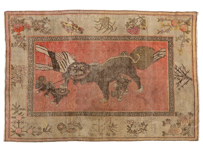 An antique Samarkand-style rug featuring a central reddish-pink panel with a dark brown animal motif, surrounded by a beige border with floral and geometric patterns.