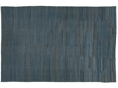 A rectangular woven rug with a textured vertical striped pattern in slate blue and charcoal gray, shown flat against a white background.