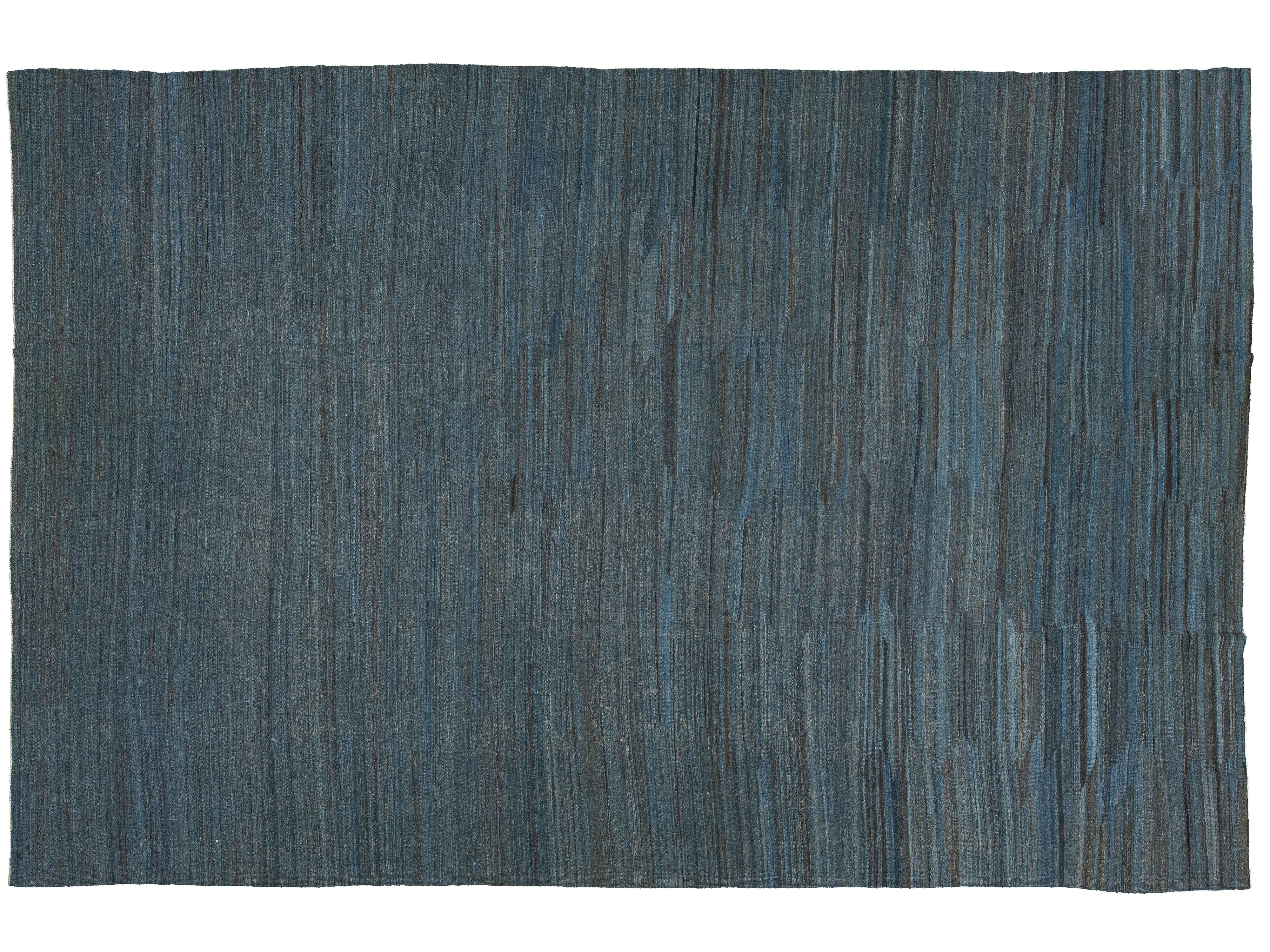 A rectangular woven rug with a textured vertical striped pattern in slate blue and charcoal gray, shown flat against a white background.