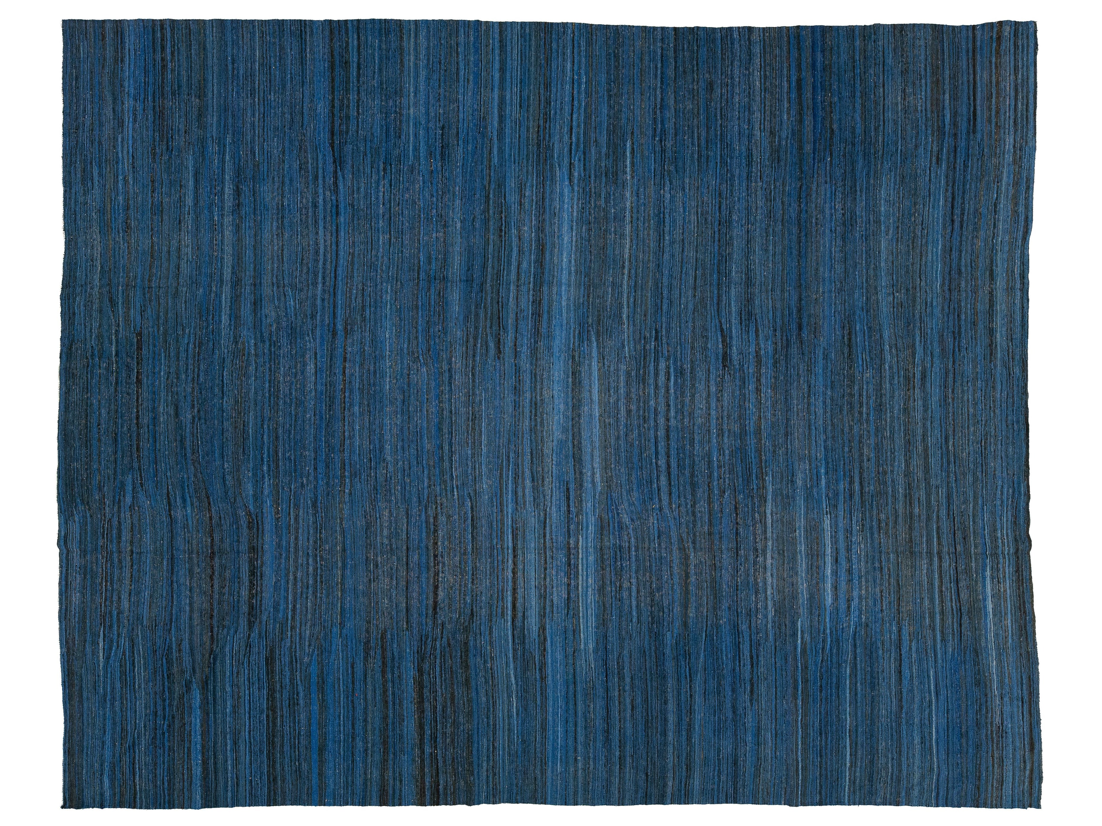 A rectangular area rug with a textured, vertically striped pattern in shades of blue, navy, and charcoal gray, shown flat against a white background.