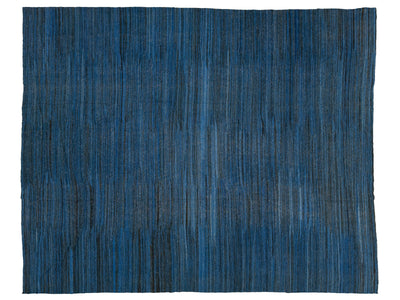 A rectangular area rug with a textured, vertically striped pattern in shades of blue, navy, and charcoal gray, shown flat against a white background.