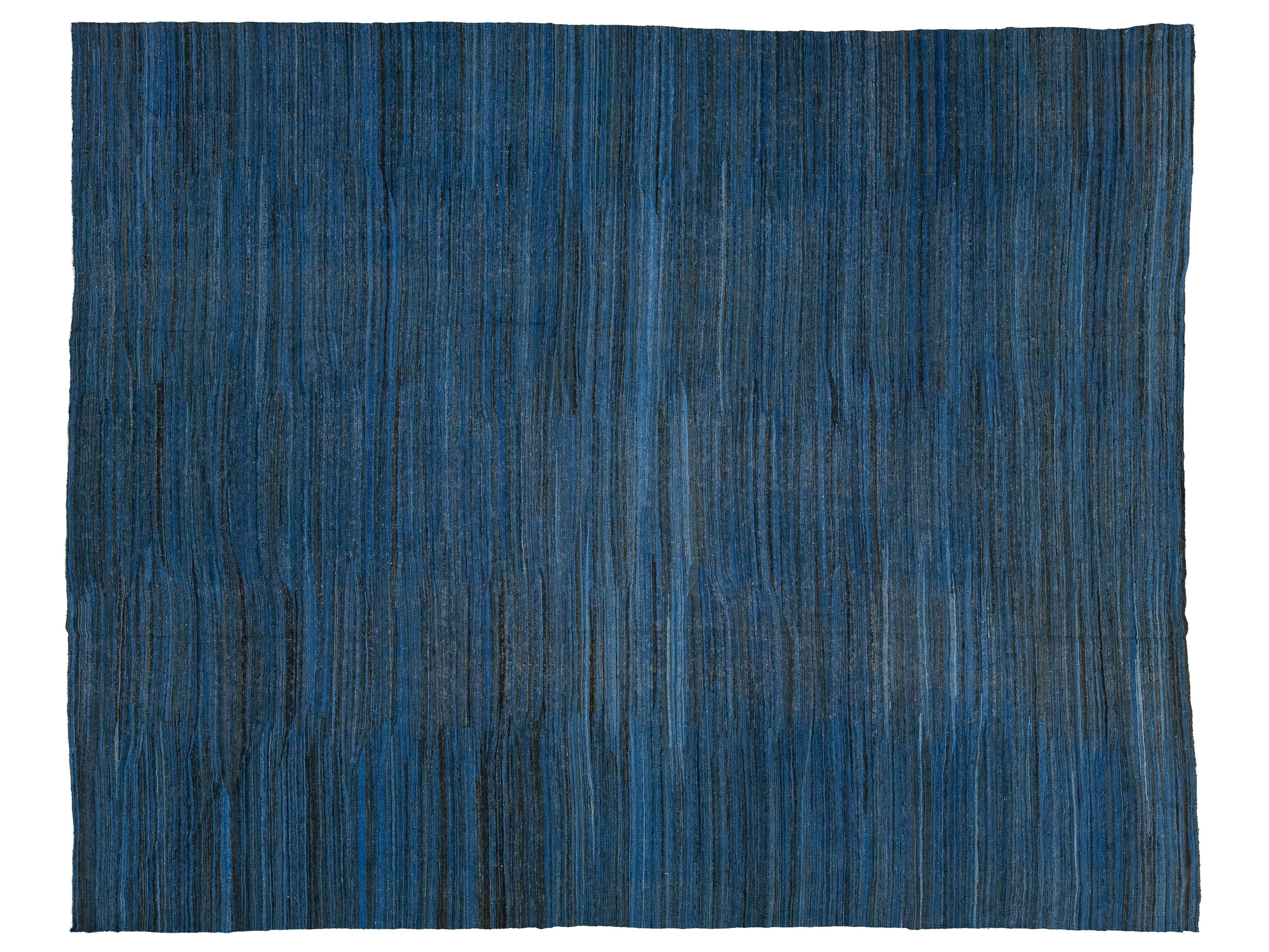 A rectangular area rug with a textured, vertically striped pattern in shades of blue, navy, and charcoal gray, shown flat against a white background.
