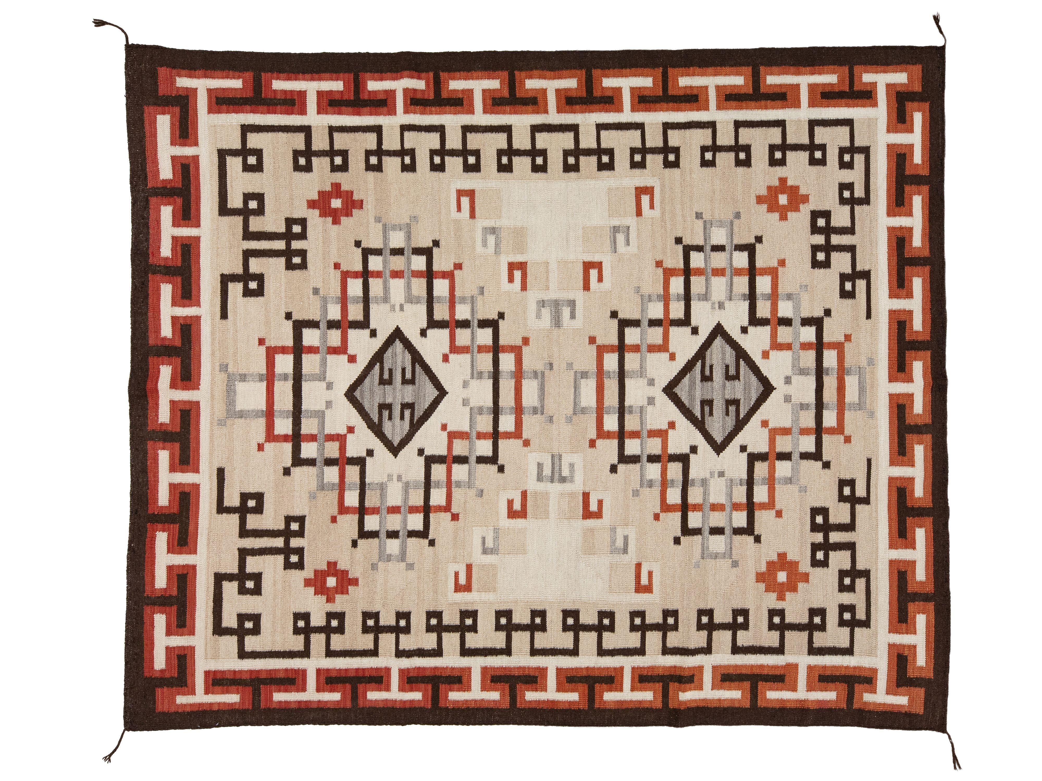 A rectangular woven rug with a Southwestern geometric pattern, featuring a cream center, brown borders, and accents of terracotta red, black, and gray.