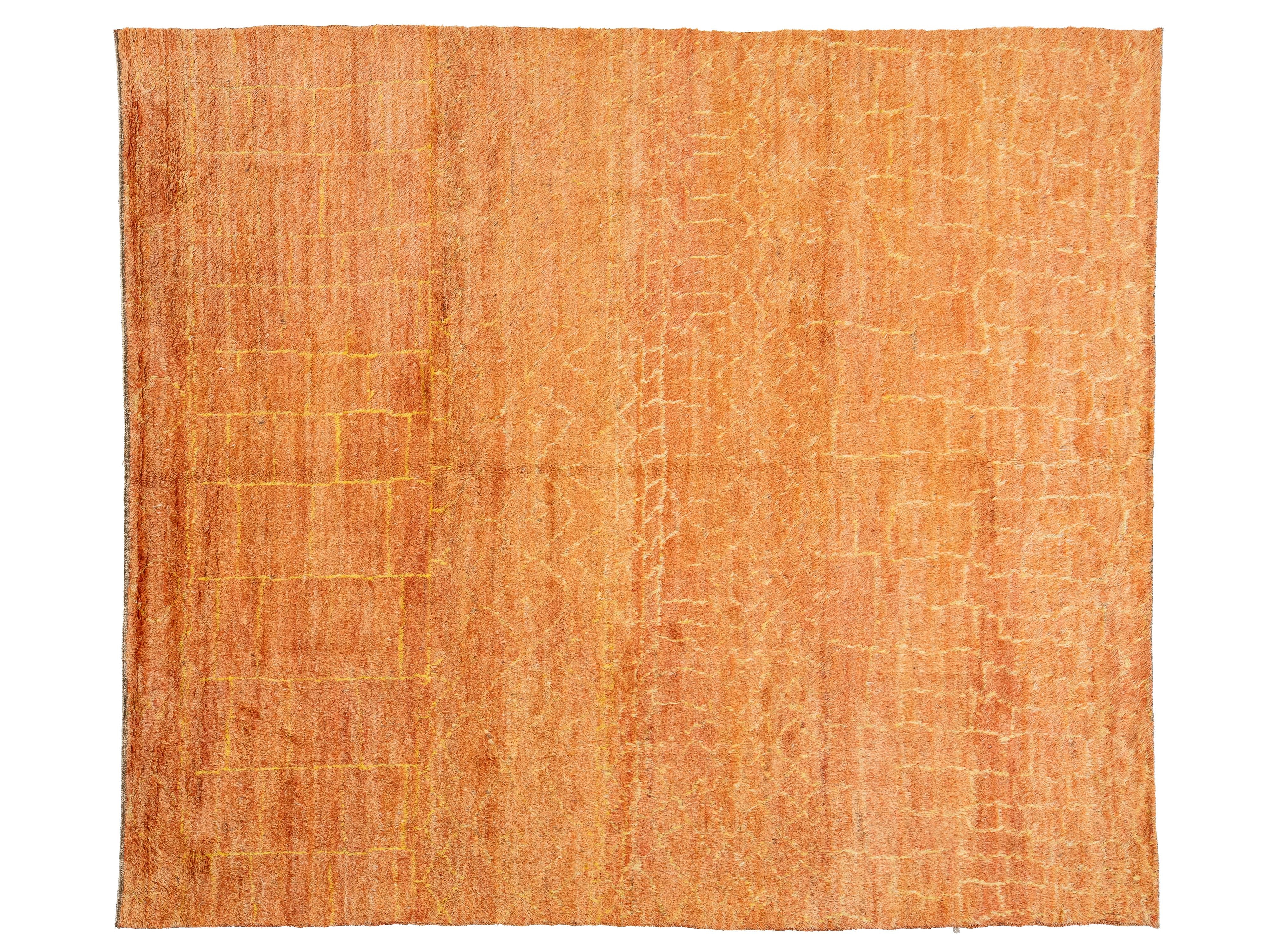 A rectangular area rug with a textured, woven surface in a warm orange and peach color palette, featuring subtle tonal variations and a subtle grid-like pattern.