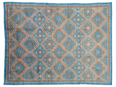 A rectangular area rug with a geometric diamond pattern in shades of blue, beige, and rust orange, finished with a matching blue border.