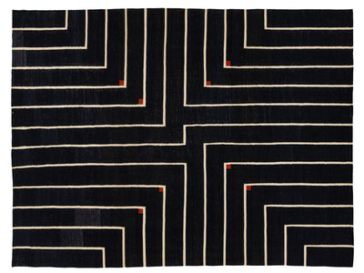 A rectangular black rug with a geometric maze-like pattern of cream lines and small red corner accents, shown flat against a white background.