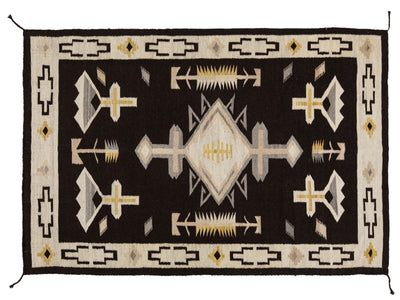 A Southwestern-style woven rug with a black central field, cream and beige geometric motifs, and yellow accents, bordered by a cream outer edge with black and yellow details.