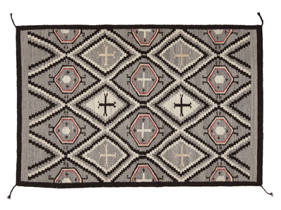 A rectangular woven rug with a Southwestern geometric pattern in gray, black, beige, and muted terracotta pink, shown flat against a white background.