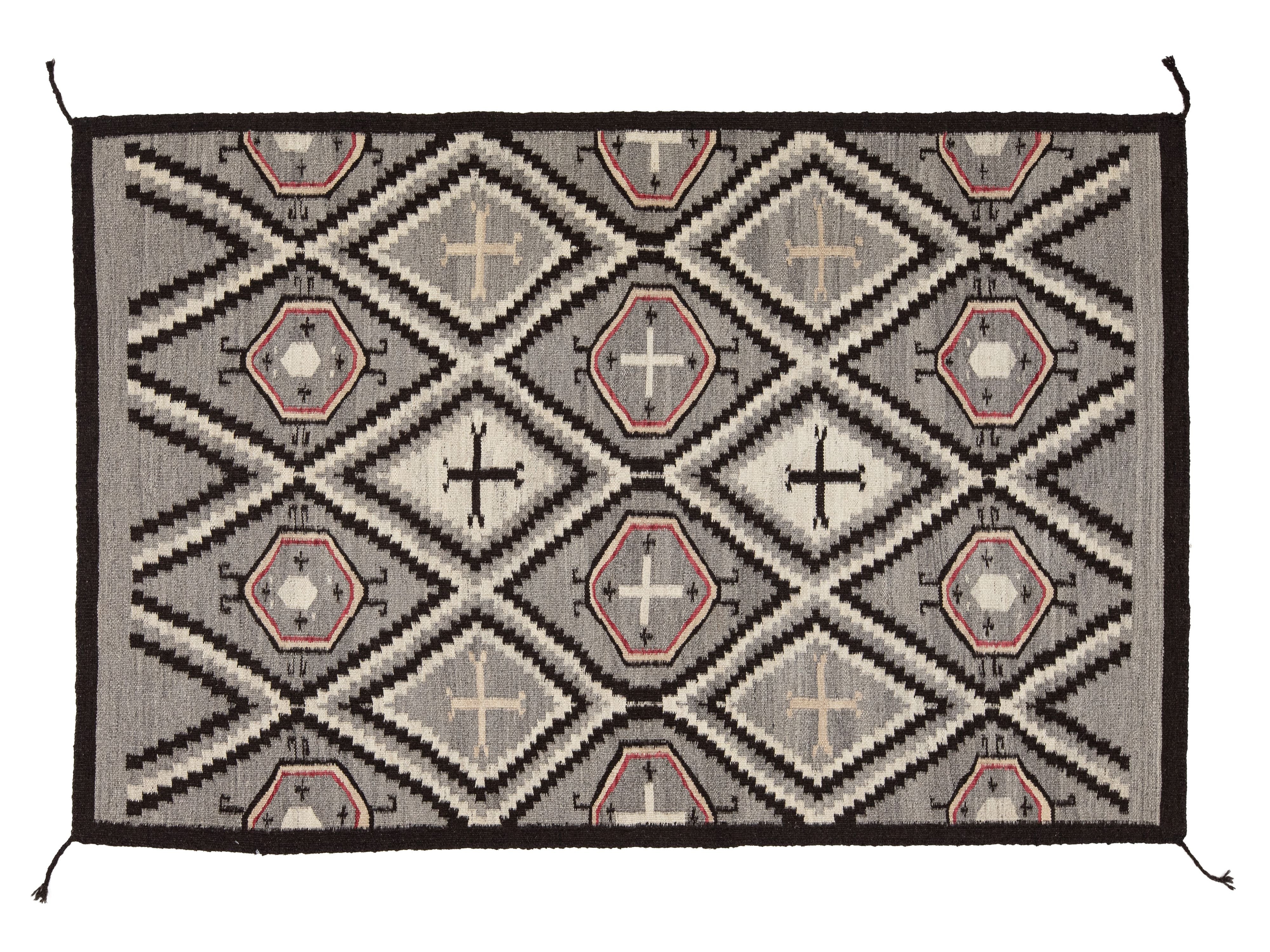A rectangular woven rug with a Southwestern geometric pattern in gray, black, beige, and muted terracotta pink, shown flat against a white background.