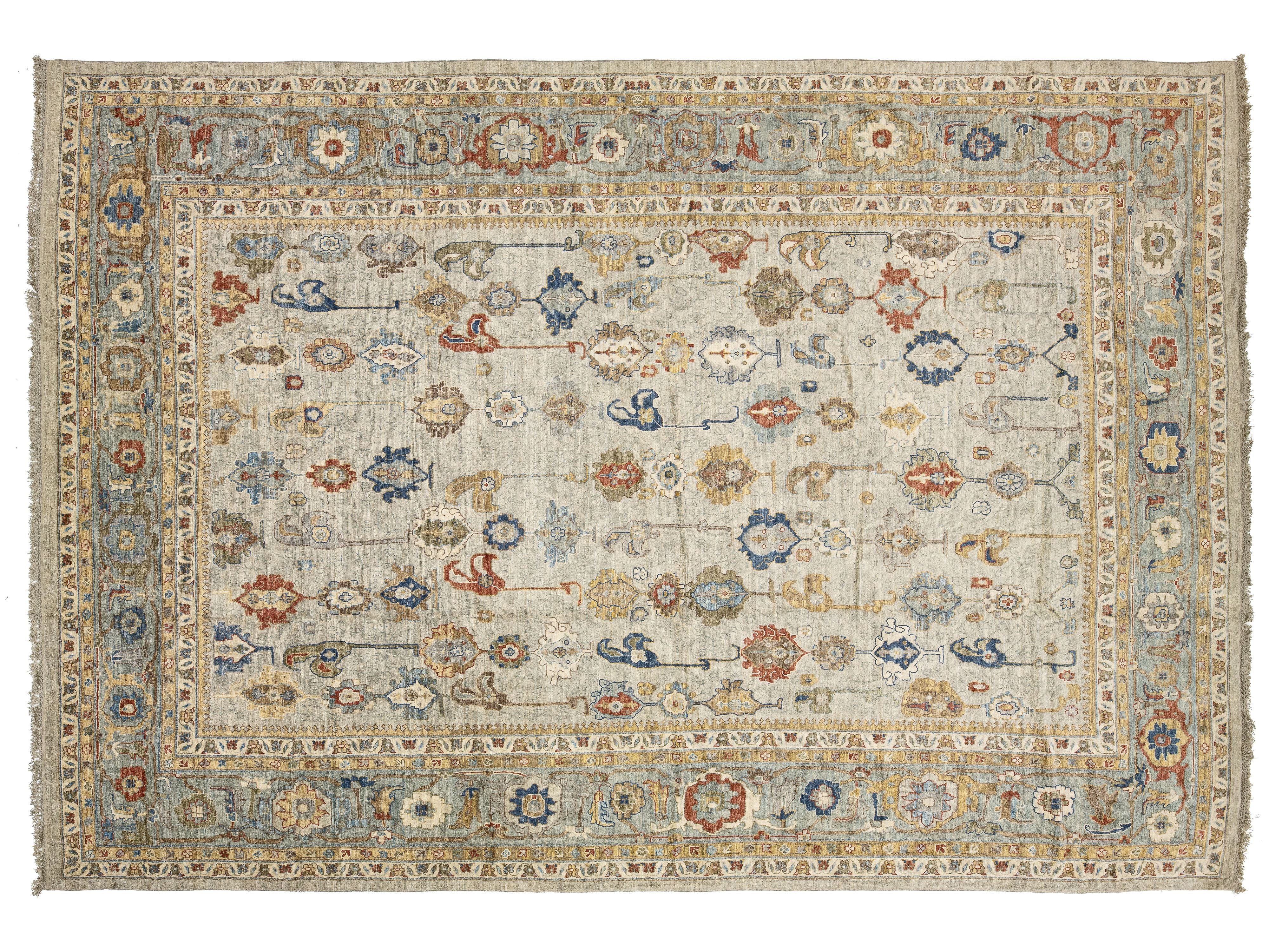 An oushak-style oriental rug with a distressed cream background, featuring intricate floral and medallion motifs in muted blue, rust red, and beige tones, complete with a detailed border and fringe.