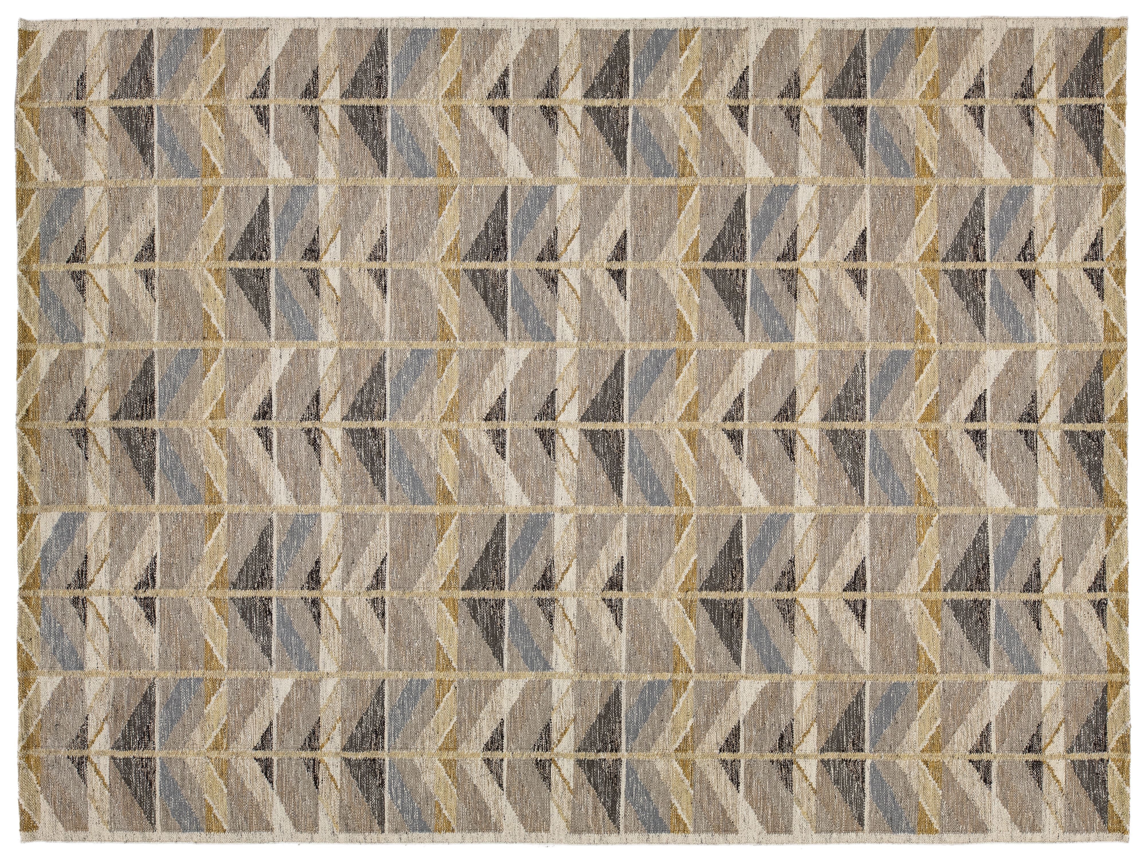 A rectangular area rug with a geometric chevron pattern in shades of beige, gray, brown, and muted blue, framed by a thin cream border.
