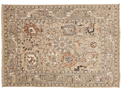 A traditional oushak-style area rug with an intricate floral and geometric pattern in beige, brown, and muted orange tones, featuring a central medallion and fringed edges.