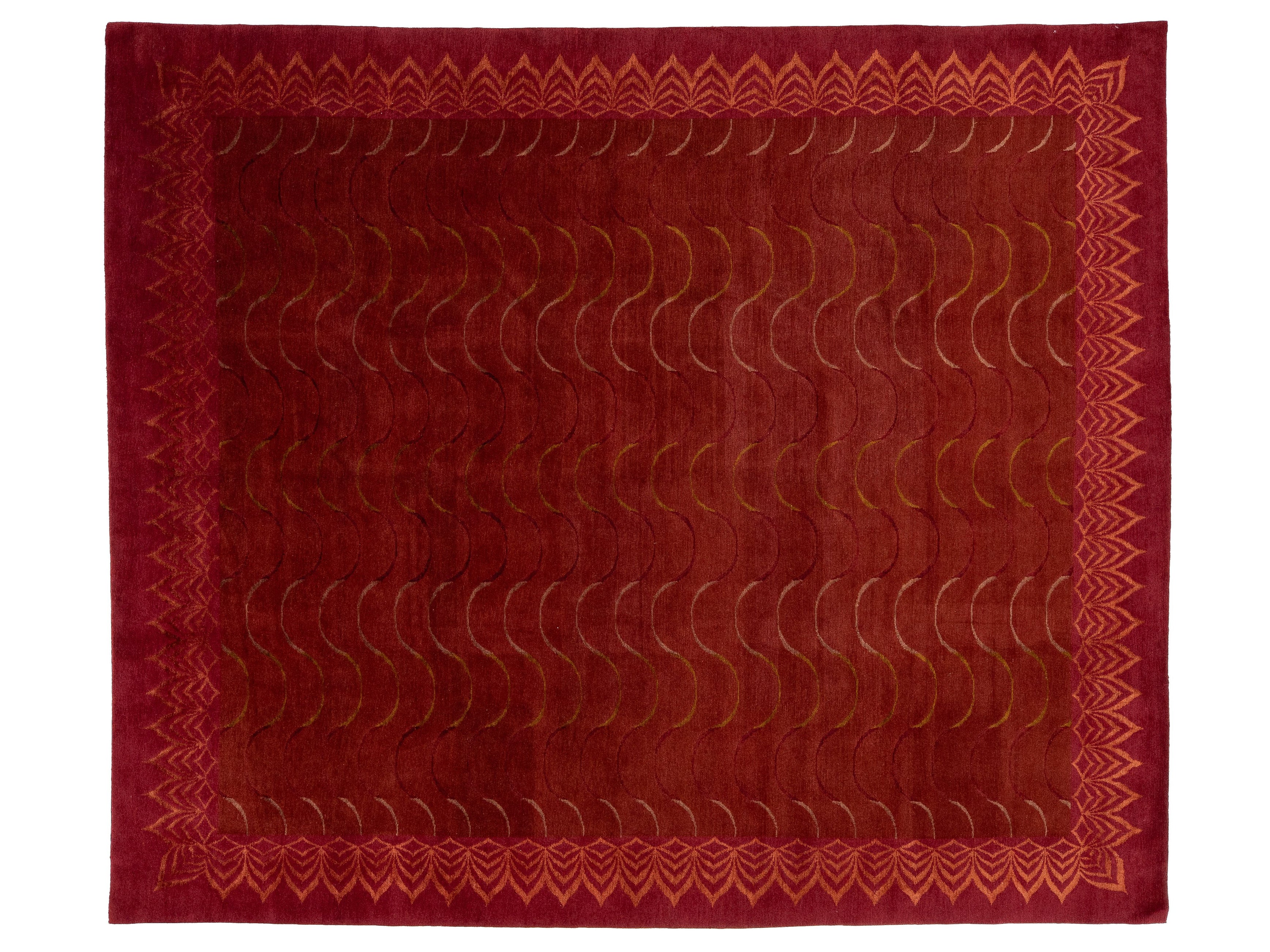 A rectangular red area rug with a textured, raised chevron and wave pattern in the center and a decorative border.