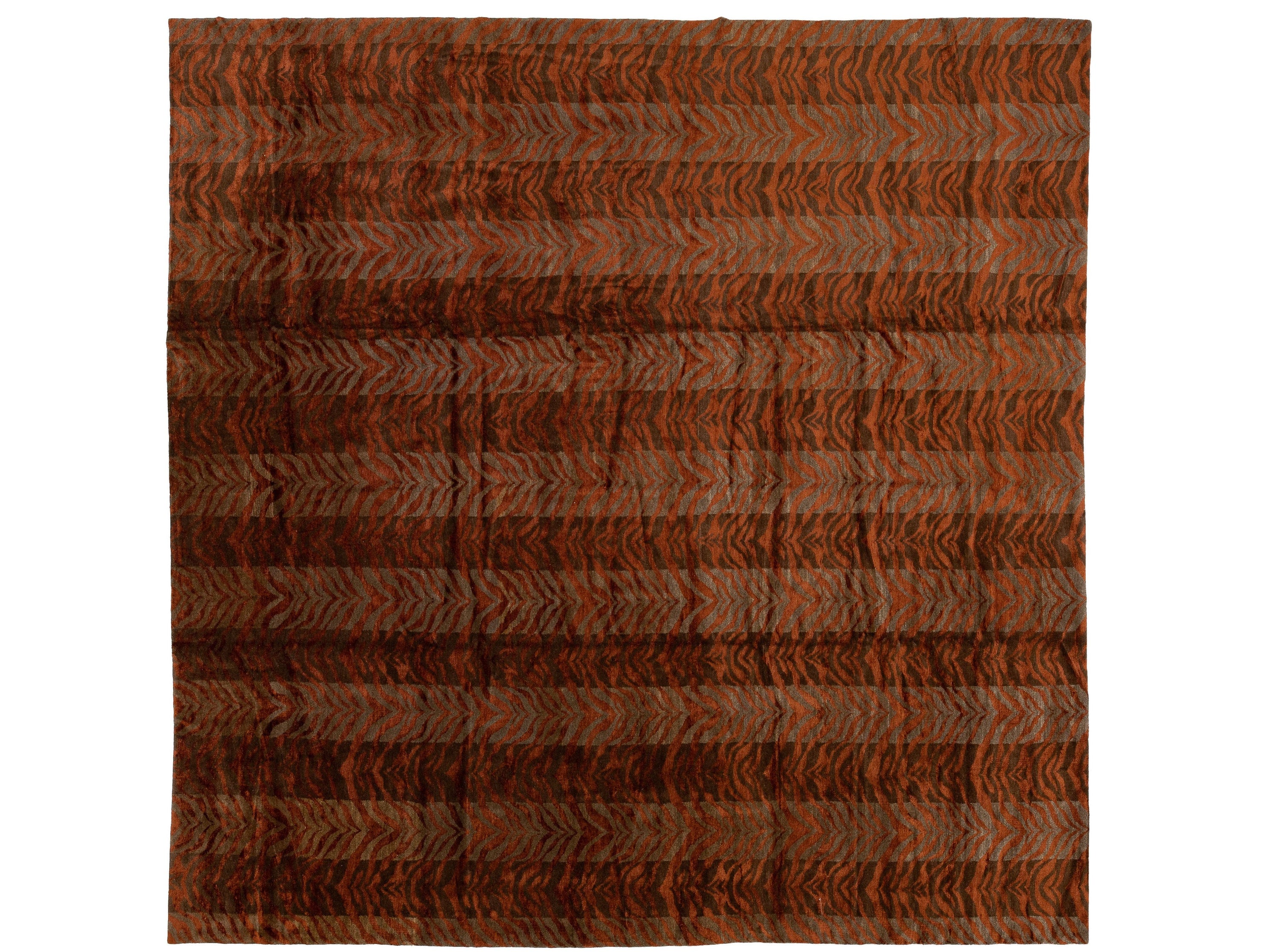A square area rug with a striped pattern featuring textured chevron or herringbone motifs in rust orange, brown, and dark charcoal gray.