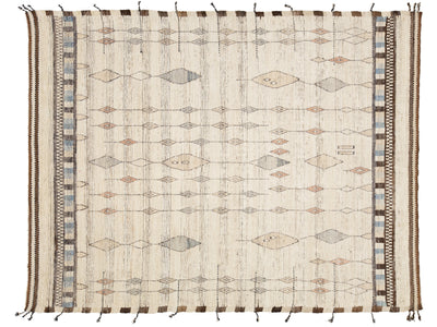 A rectangular woven rug with a cream base and geometric diamond motifs in muted brown, beige, gray, and blue, finished with fringe tassels on the sides.