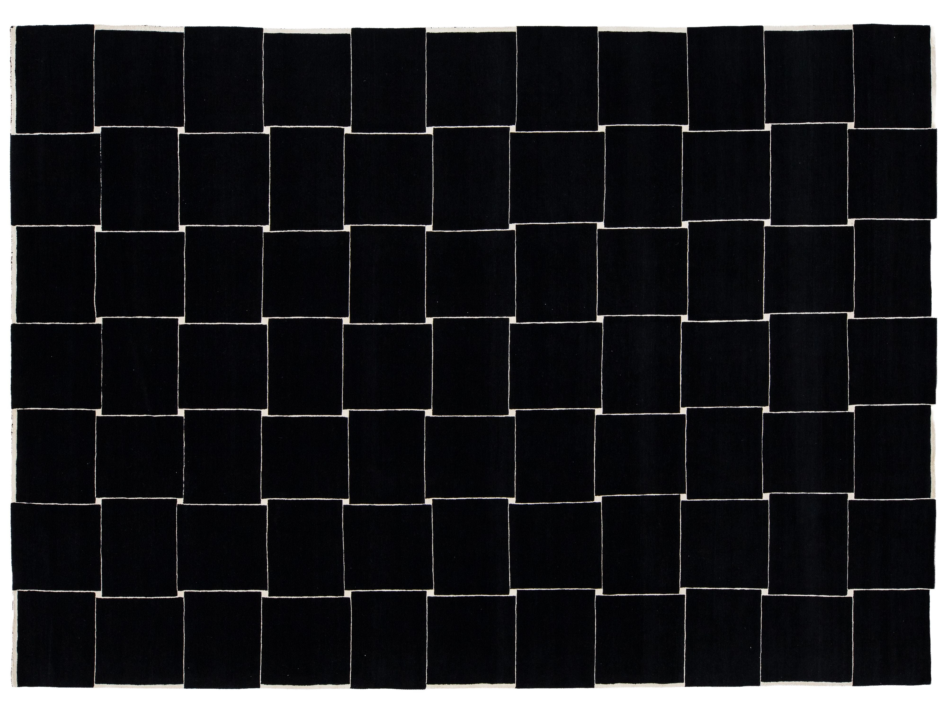 A rectangular black woven rug with a geometric basketweave pattern created by alternating black and off-white woven squares.