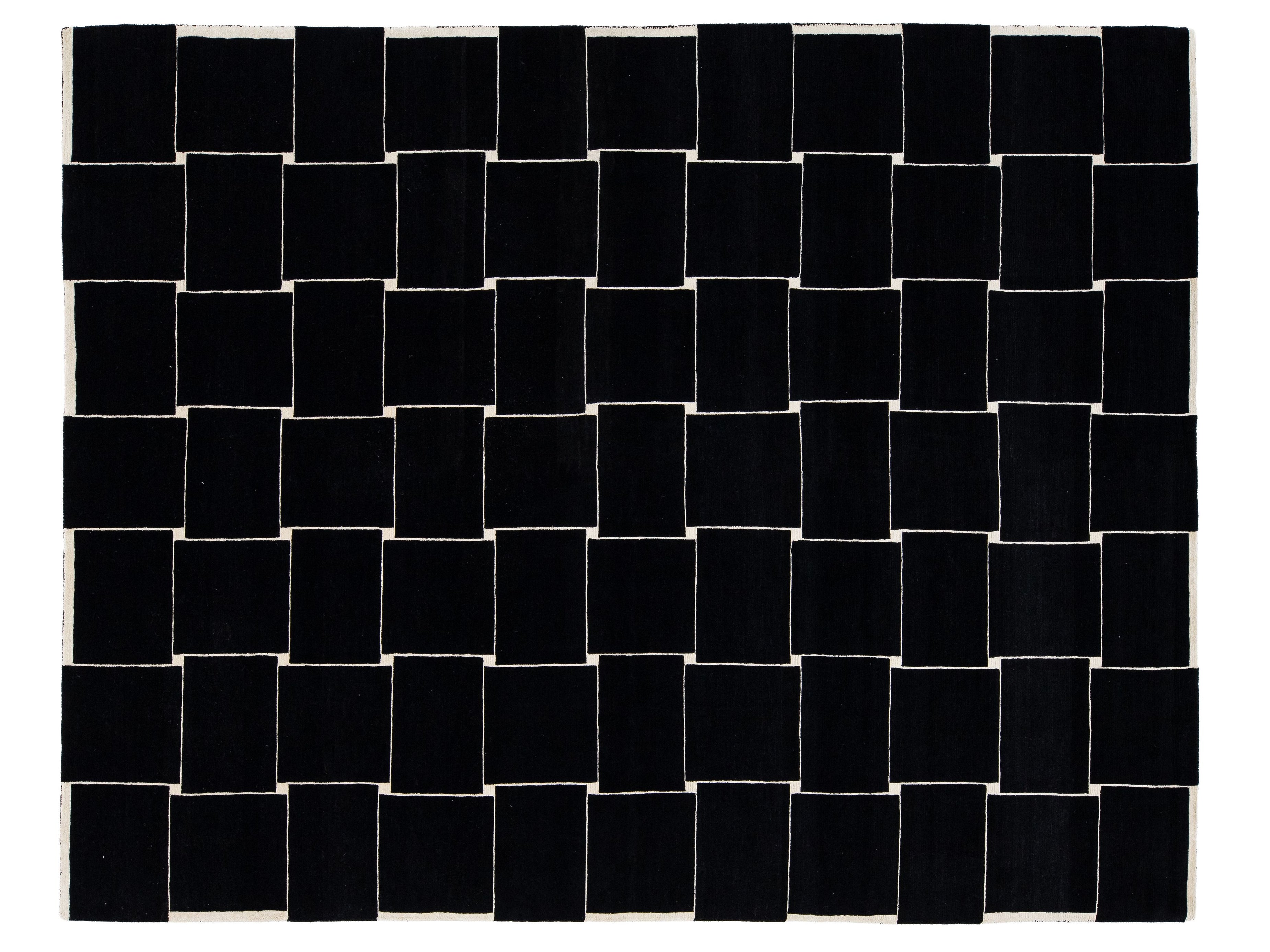 A rectangular black rug with a white woven border and a geometric basketweave pattern of alternating black and white squares.
