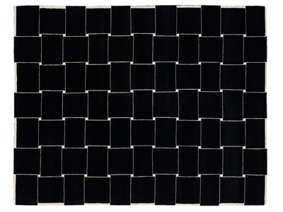 A rectangular black rug with a white woven border and a geometric basketweave pattern of alternating black and white squares.
