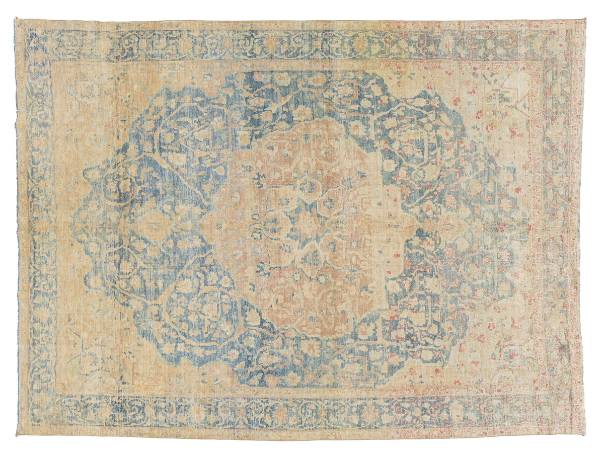 A distressed traditional area rug with a faded central medallion, featuring a warm beige base color with faded blue, dusty pink, and light orange floral patterns.