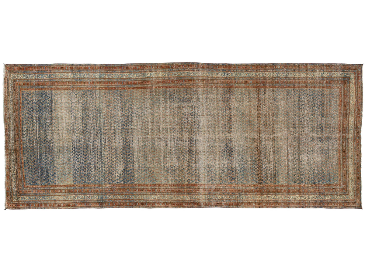 A rectangular vintage-style area rug with an intricate, distressed pattern in muted tones of blue, beige, brown, and rust orange.