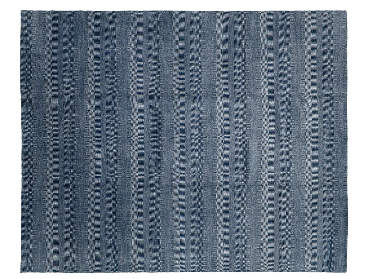 A rectangular modern savannah indigo blue rug with a textured, horizontally ribbed pattern.