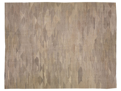 A rectangular area rug with an abstract geometric pattern in shades of beige, taupe, and brown.