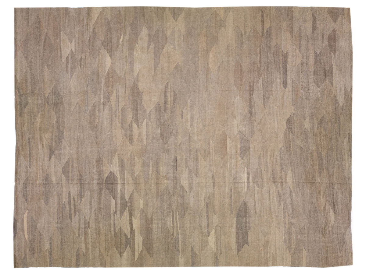A rectangular area rug with an abstract geometric pattern in shades of beige, taupe, and brown.