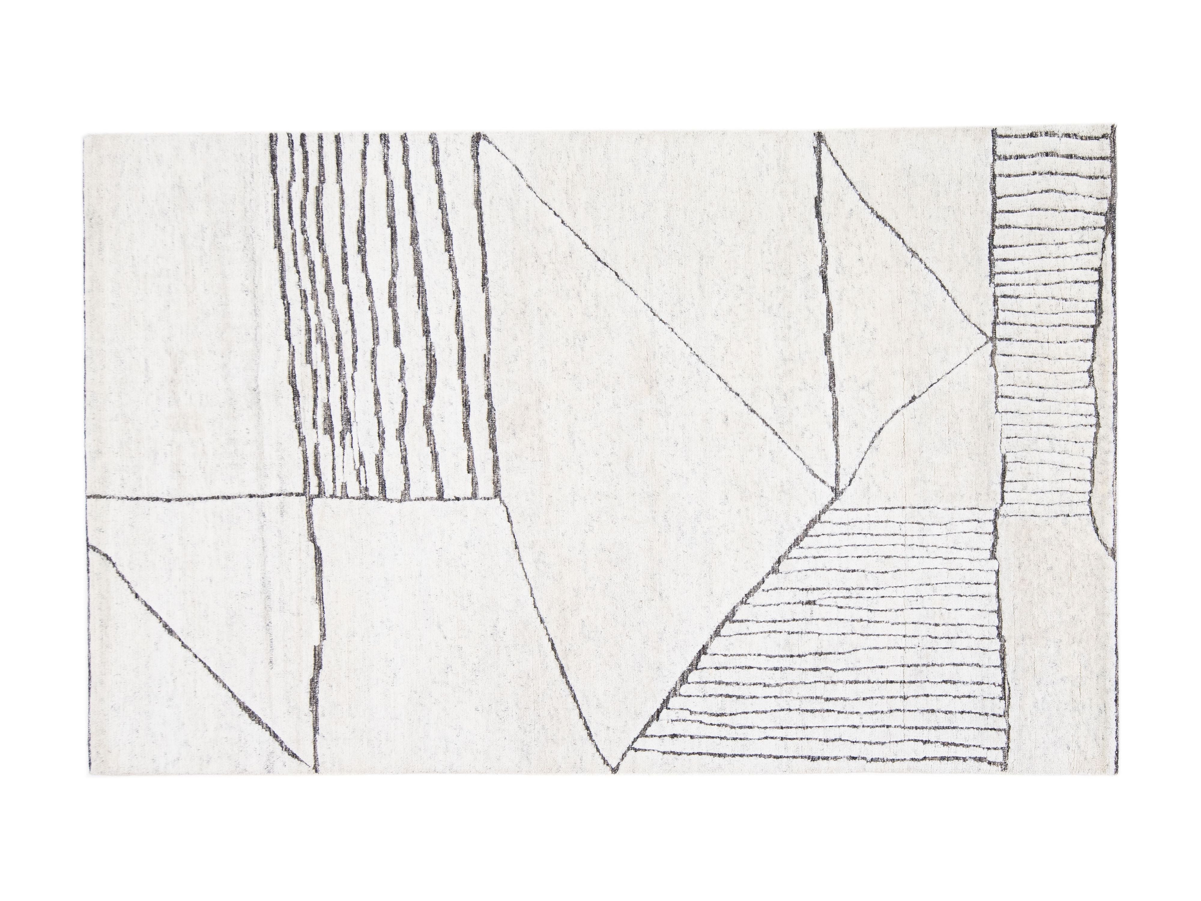 An abstract area rug with a geometric pattern featuring black hand-drawn lines on an off-white background.