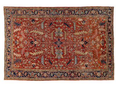 An antique rectangular traditional oriental rug with a warm rust-red field, featuring a central floral medallion, ornate borders, and muted blue, beige, and green accents.