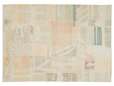 An abstract area rug with a patchwork design in soft pastel tones of beige, cream, peach, sage green, and light blue, shown flat against a white background.