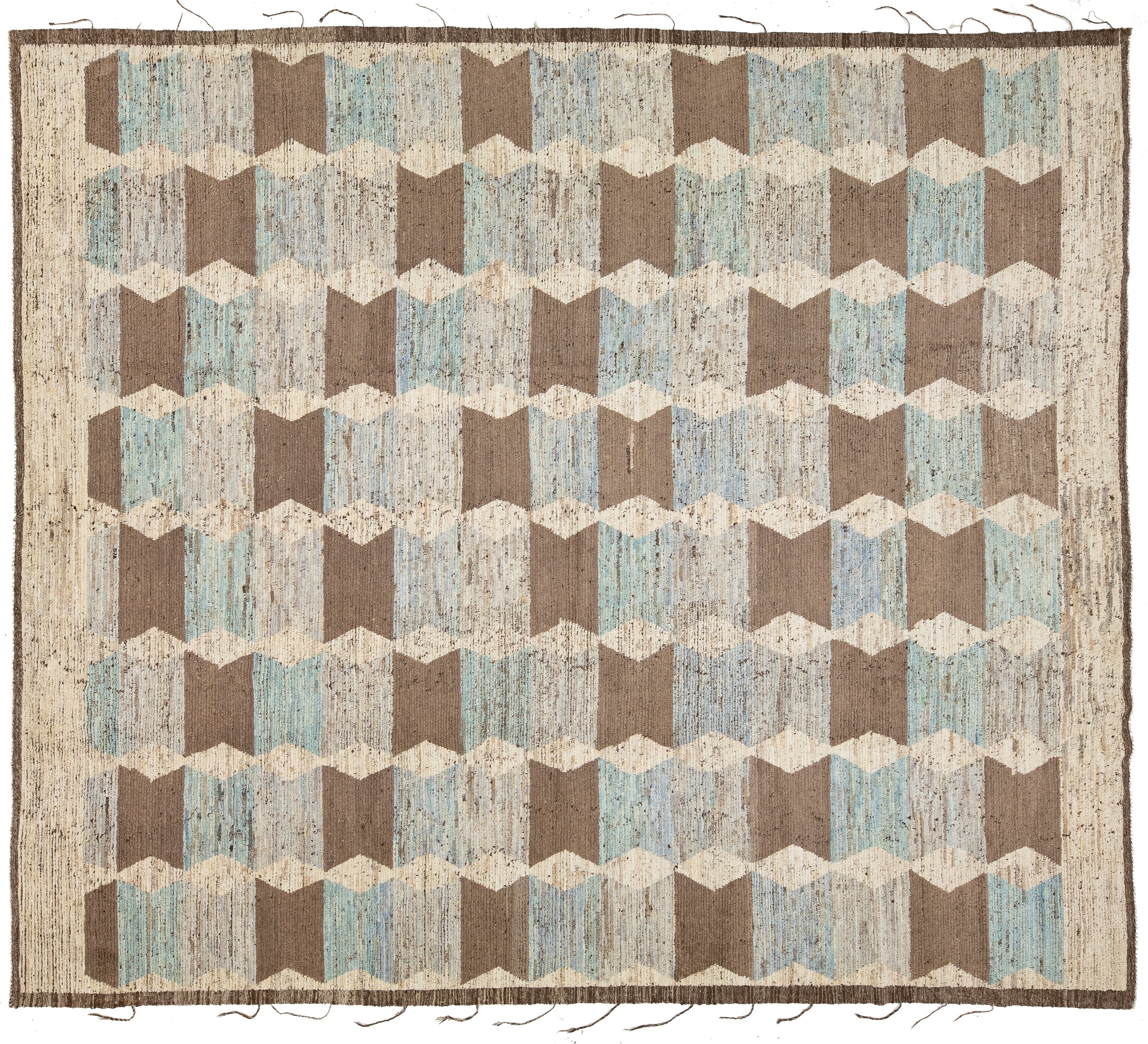 An area rug with a geometric cube pattern in shades of brown, beige, and light blue, featuring a fringed border.