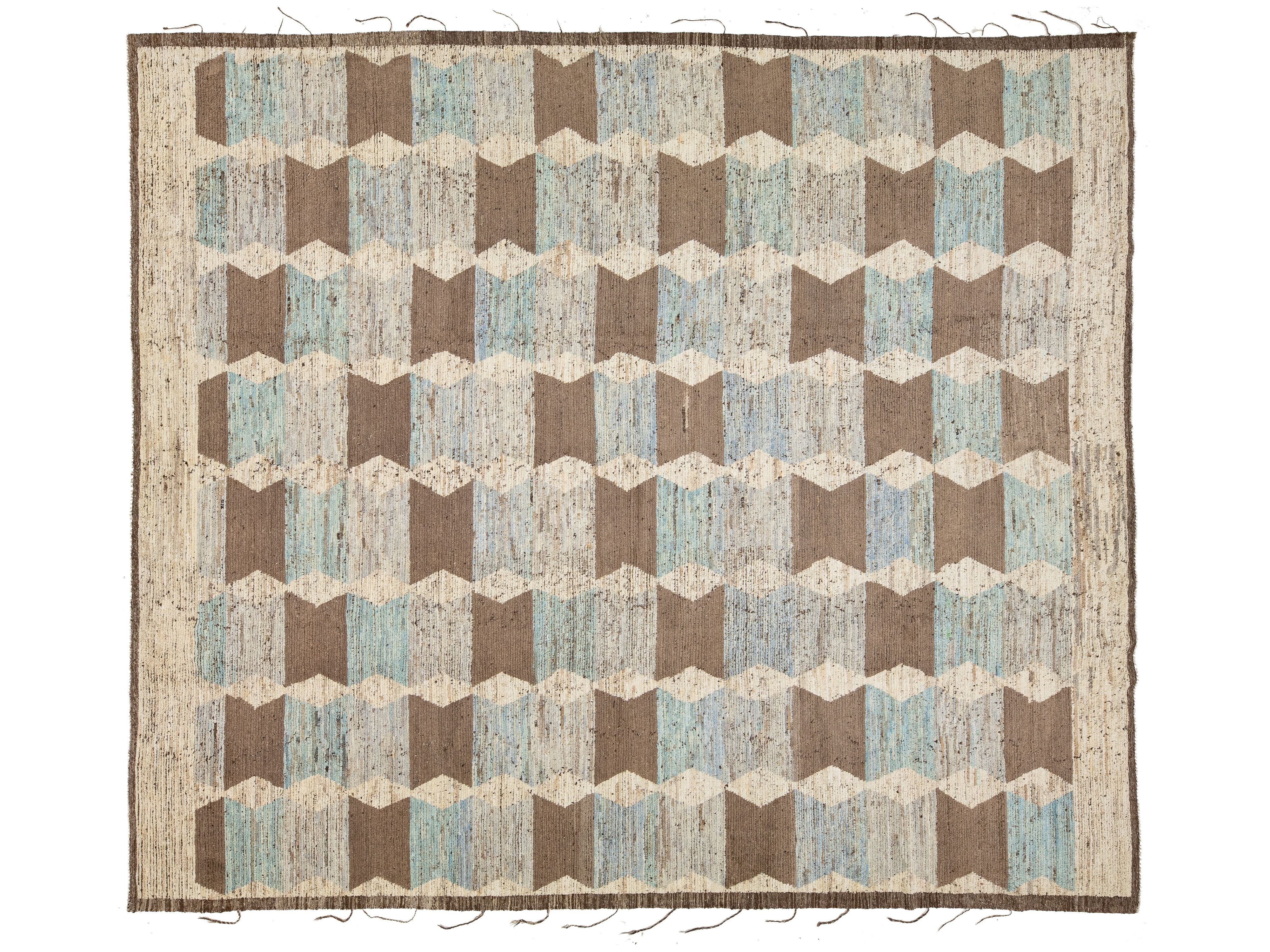 An area rug with a geometric cube pattern in shades of brown, beige, and light blue, featuring a fringed border.