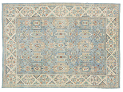 A rectangular area rug with a traditional ornamental pattern, featuring a light blue center field, beige borders, and accents of rust red, navy, and gray.