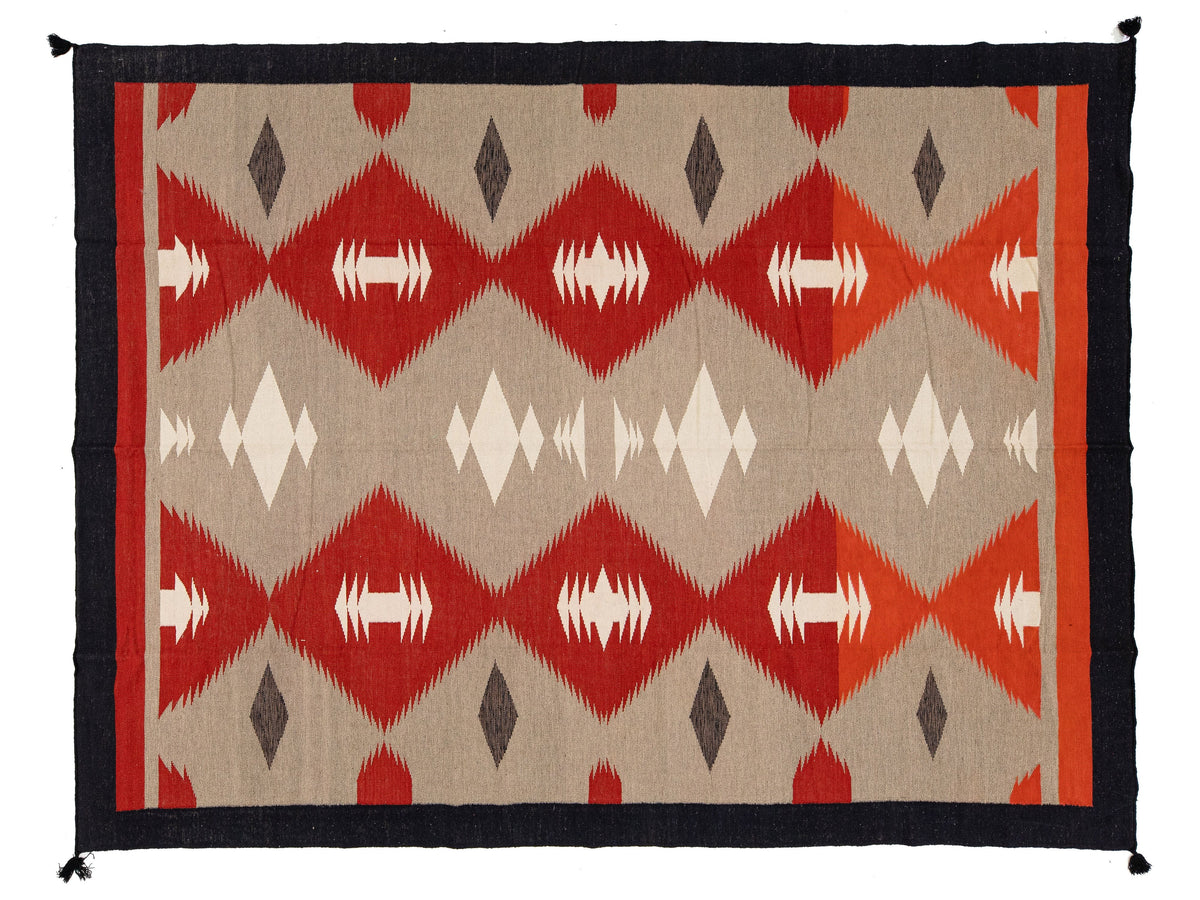 A rectangular woven rug with a Southwestern geometric pattern, featuring red and orange diamonds, white and gray accents, and a black border.
