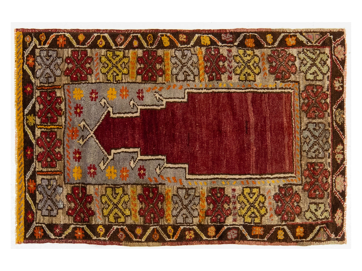A traditional rectangular area rug with a central red mihrab motif, surrounded by a gray inner border and a wide multicolor geometric outer border in brown, gold, and cream.