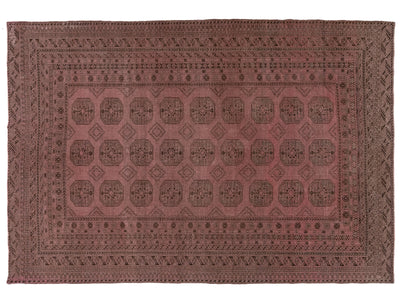 A rectangular vintage rug with a dusty rose and dark brown geometric pattern, featuring a central field of medallions and a detailed border.