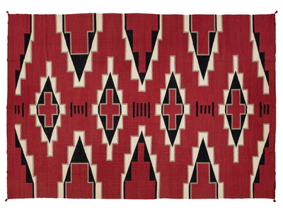 A rectangular woven rug with a bold geometric Southwestern-style pattern in red, black, and cream.