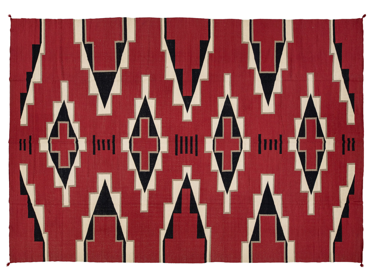 A rectangular woven rug with a bold geometric Southwestern-style pattern in red, black, and cream.