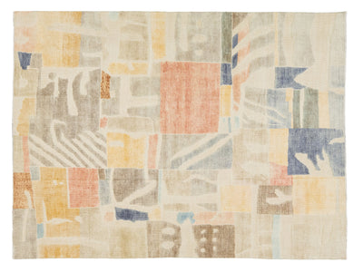 A rectangular area rug featuring an abstract, patchwork-like geometric pattern in muted tones of beige, cream, dusty blue, terracotta, mustard yellow, and brown.