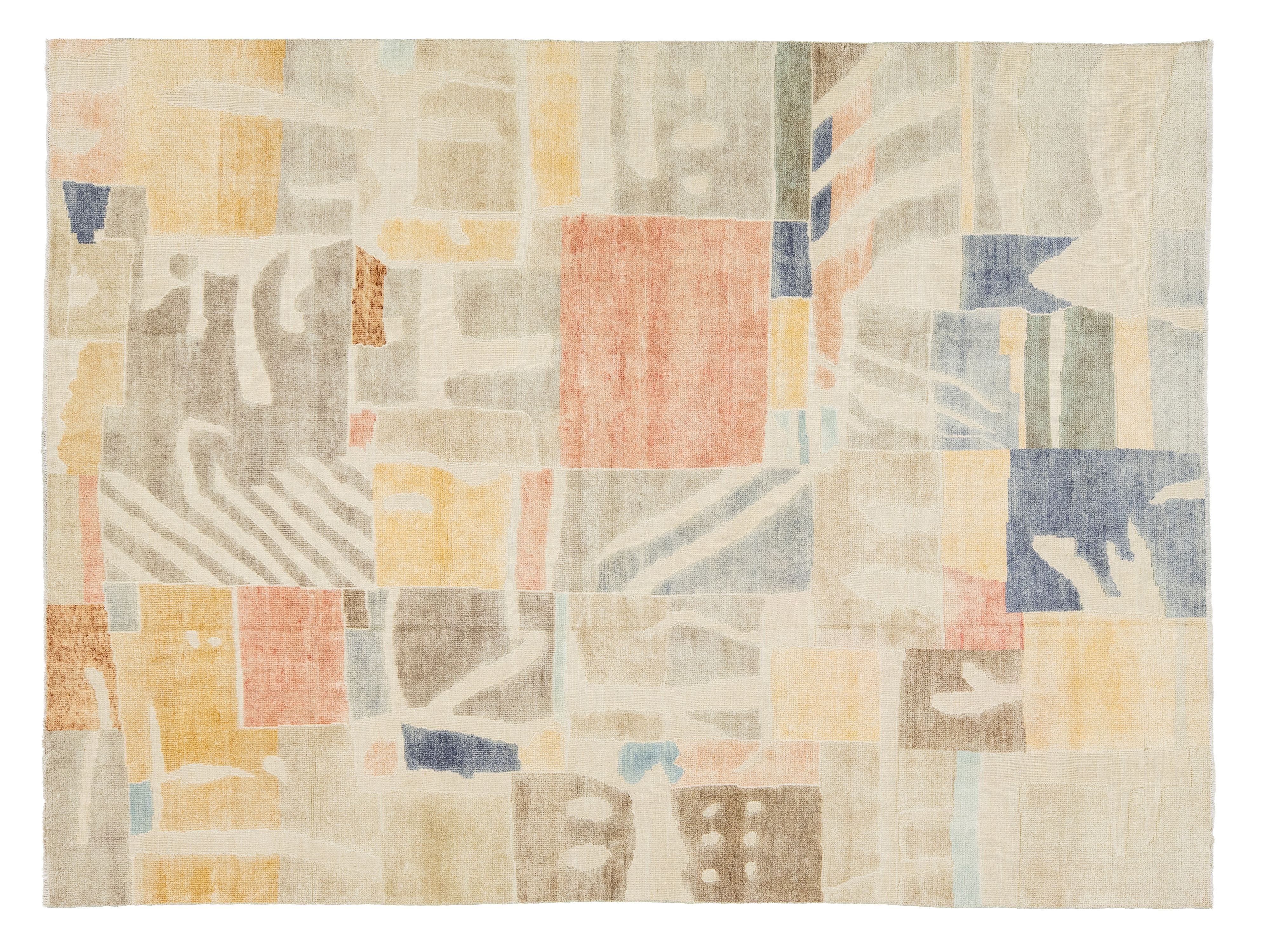 A rectangular area rug featuring an abstract, patchwork-like geometric pattern in muted tones of beige, cream, dusty blue, terracotta, mustard yellow, and brown.