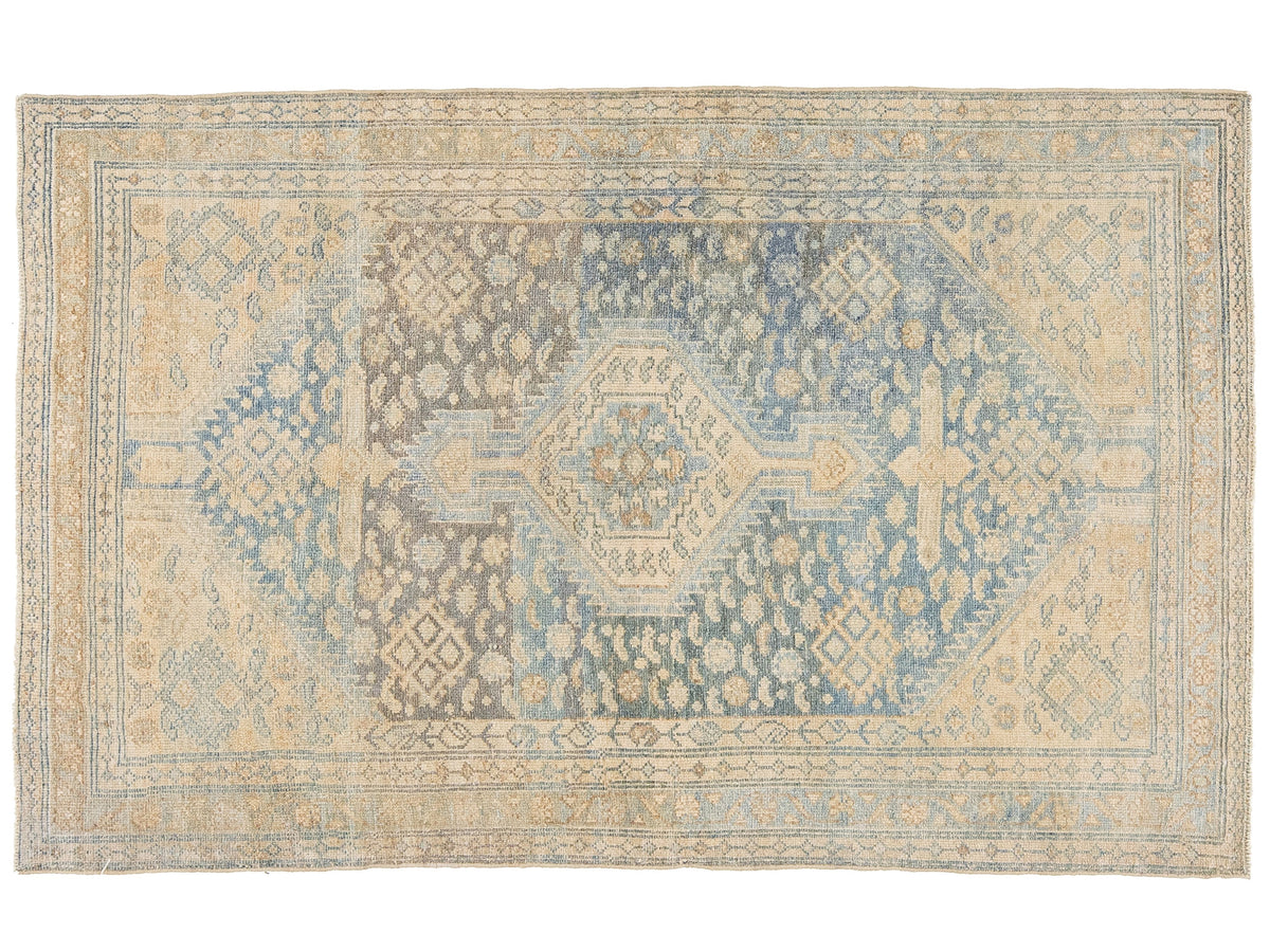 A rectangular antique area rug with a distressed medallion pattern in muted blue, beige, and gray tones, shown flat against a white background.