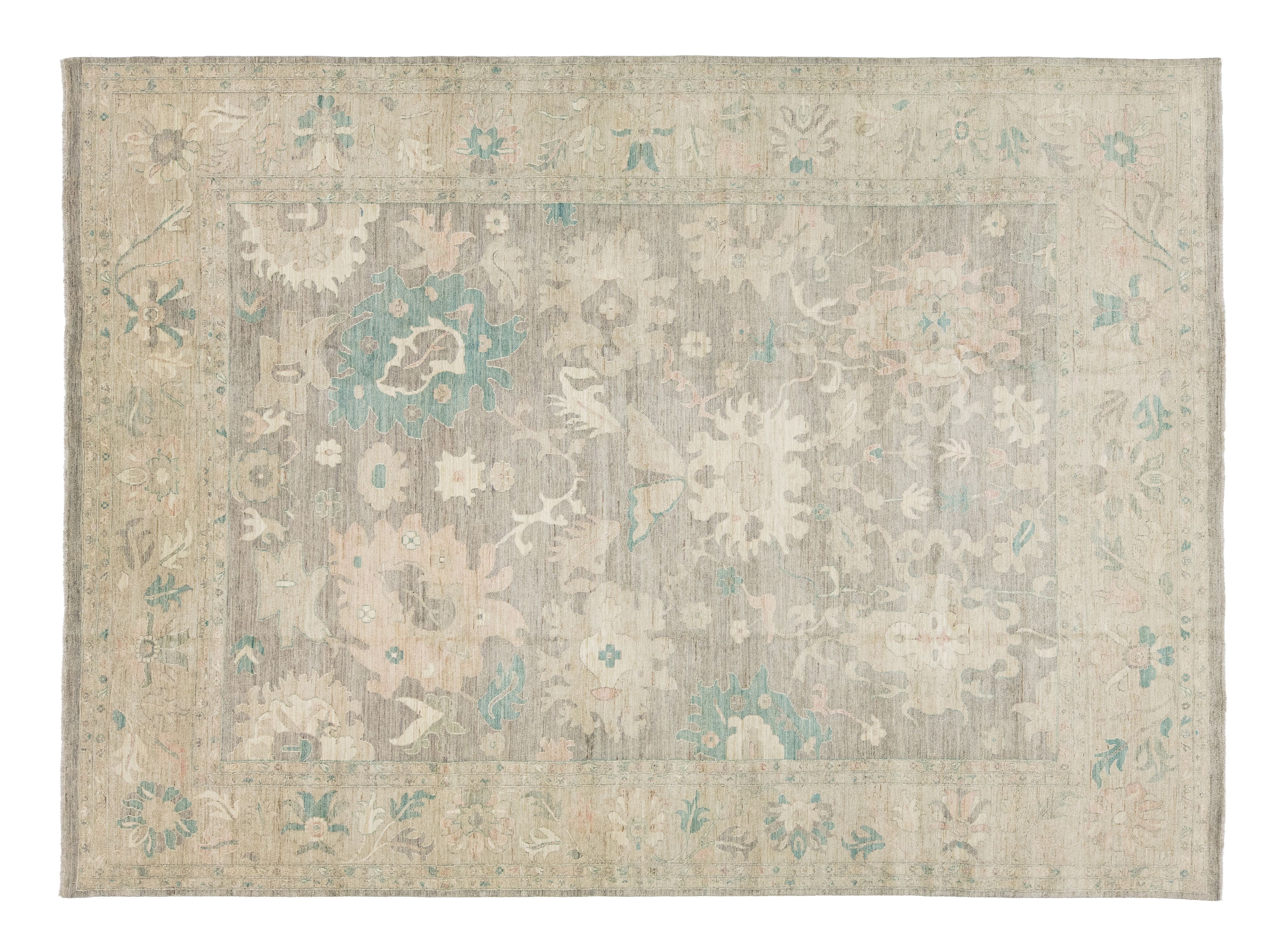 A rectangular area rug, traditional pattern in muted beige, gray, and soft teal blue.