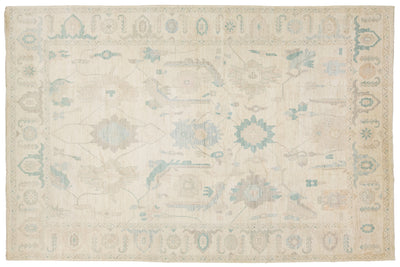 A rectangular area rug with a traditional pattern in cream, beige, light blue, and muted gray tones.