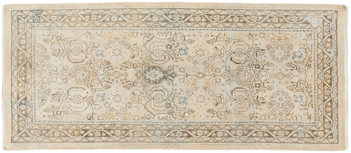 A rectangular vintage area rug with an intricate traditional floral and medallion pattern, featuring a cream background with beige, brown, and muted blue-gray details.