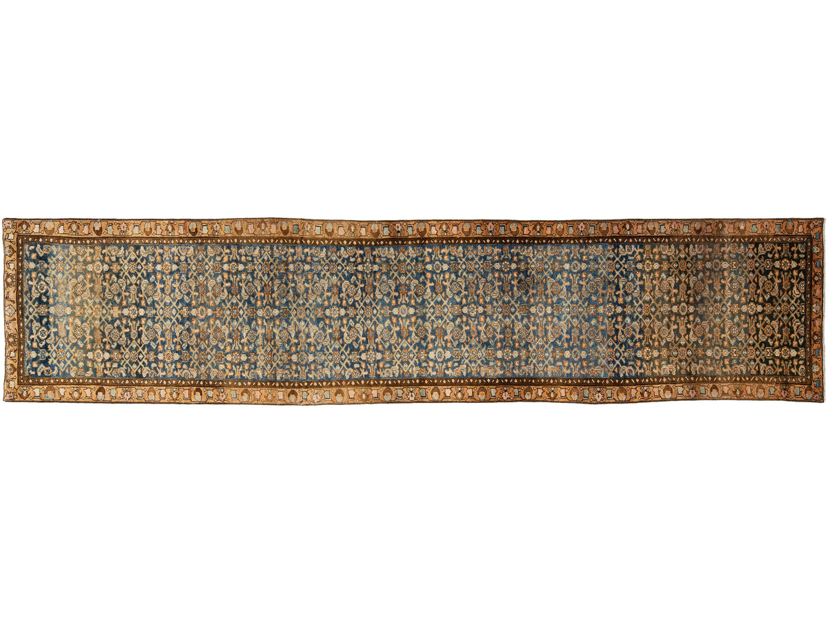A runner rug with an intricate traditional pattern in shades of blue, beige, brown, and gold, shown flat against a white background.