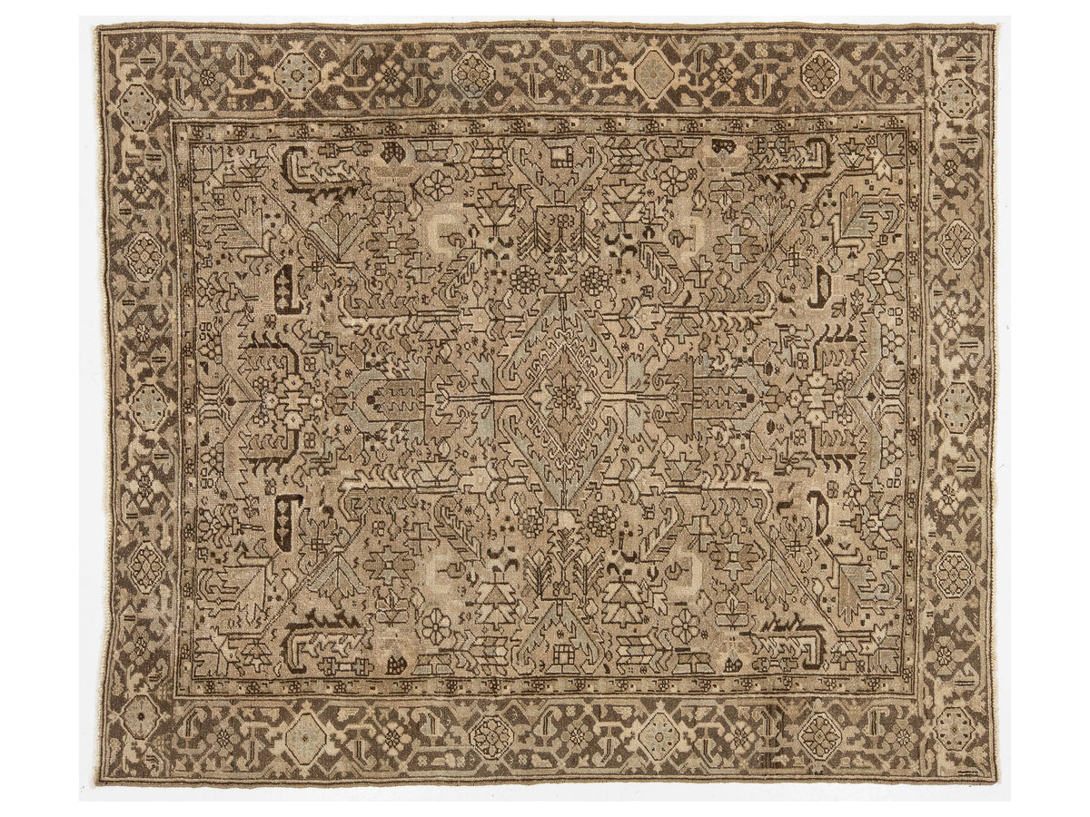 An vinatge oriental rug with an intricate, symmetrical floral and geometric pattern in shades of beige, brown, and gray, shown flat against a white background.