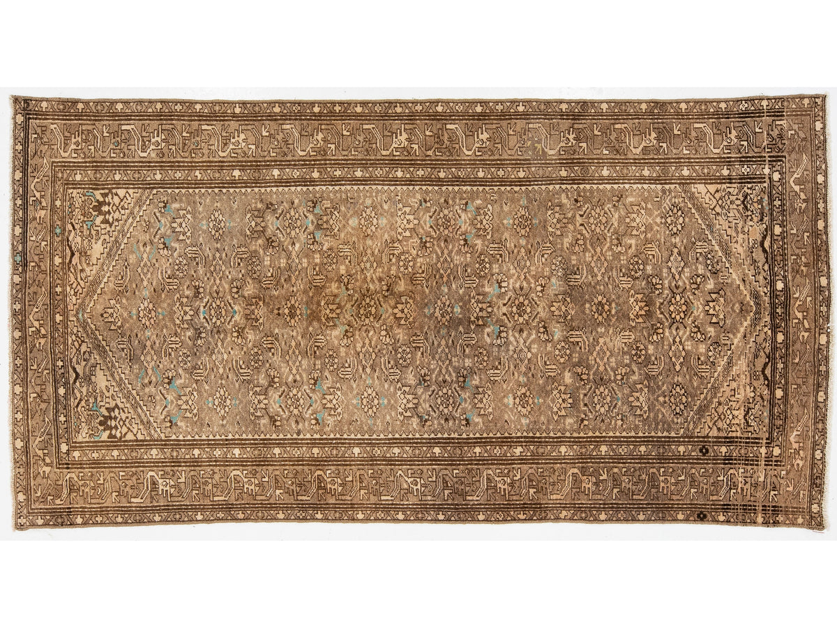 An vintage area rug with an intricate floral and geometric pattern in shades of brown, beige, and muted turquoise blue, shown flat against a white background.